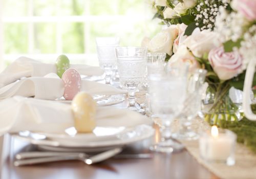 A beautifully set table with floral arrangements, glassware, and decorated eggs on plates, ready for a special occasion or celebration.